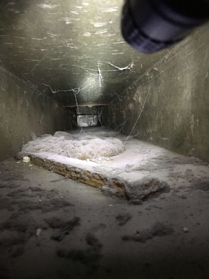 Residential sheet-metal air duct with heavy dust and debris before cleaning