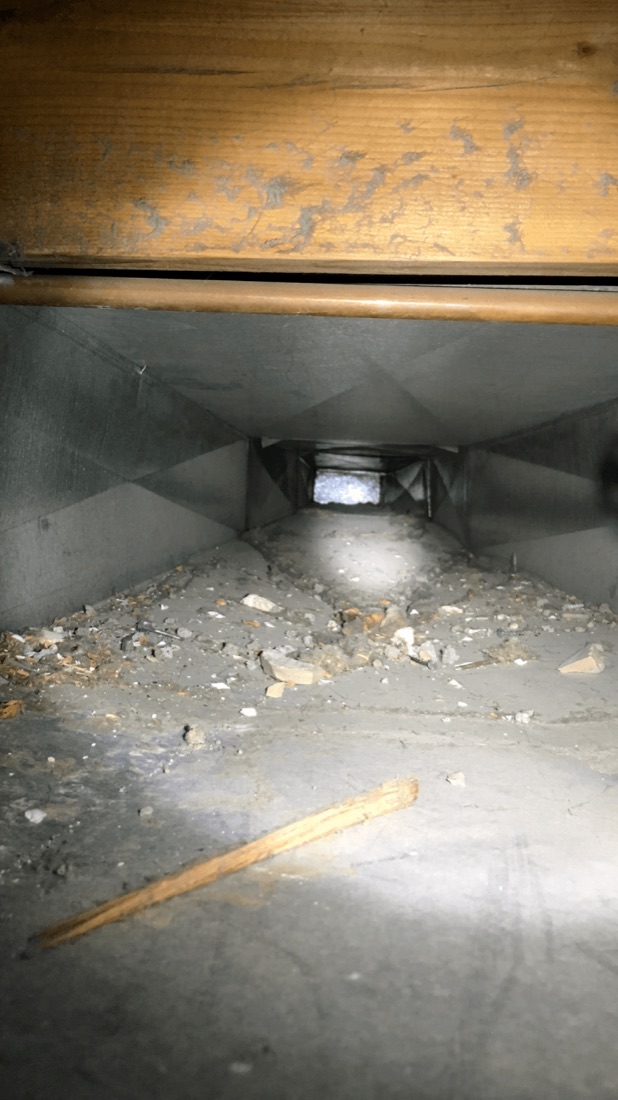 Sheet-metal air duct containing construction debris before cleaning