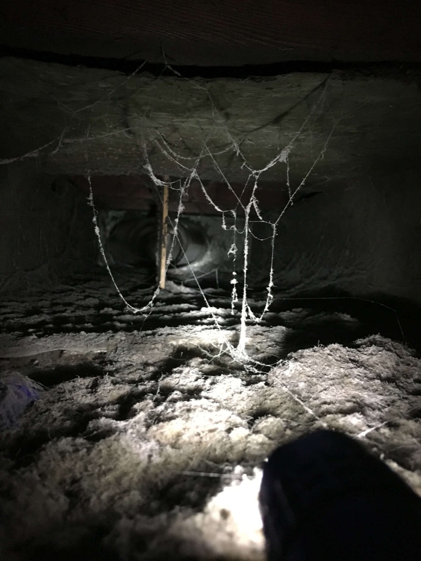 Residential air duct with dust buildup and cobwebs before cleaning